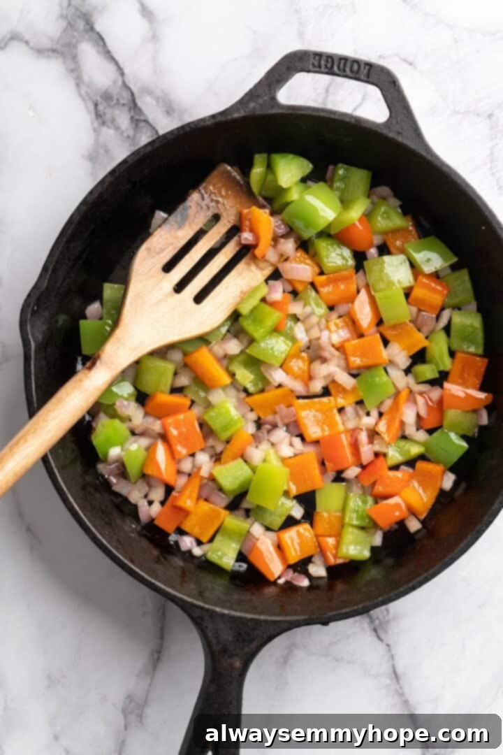 This vegan chili cornbread casserole is one of the BEST casseroles ever! The secret? Sweet, crispy cornbread baked on top of delicious chili. Bell peppers and onions cooking in a large skillet, beginning to soften and turn golden