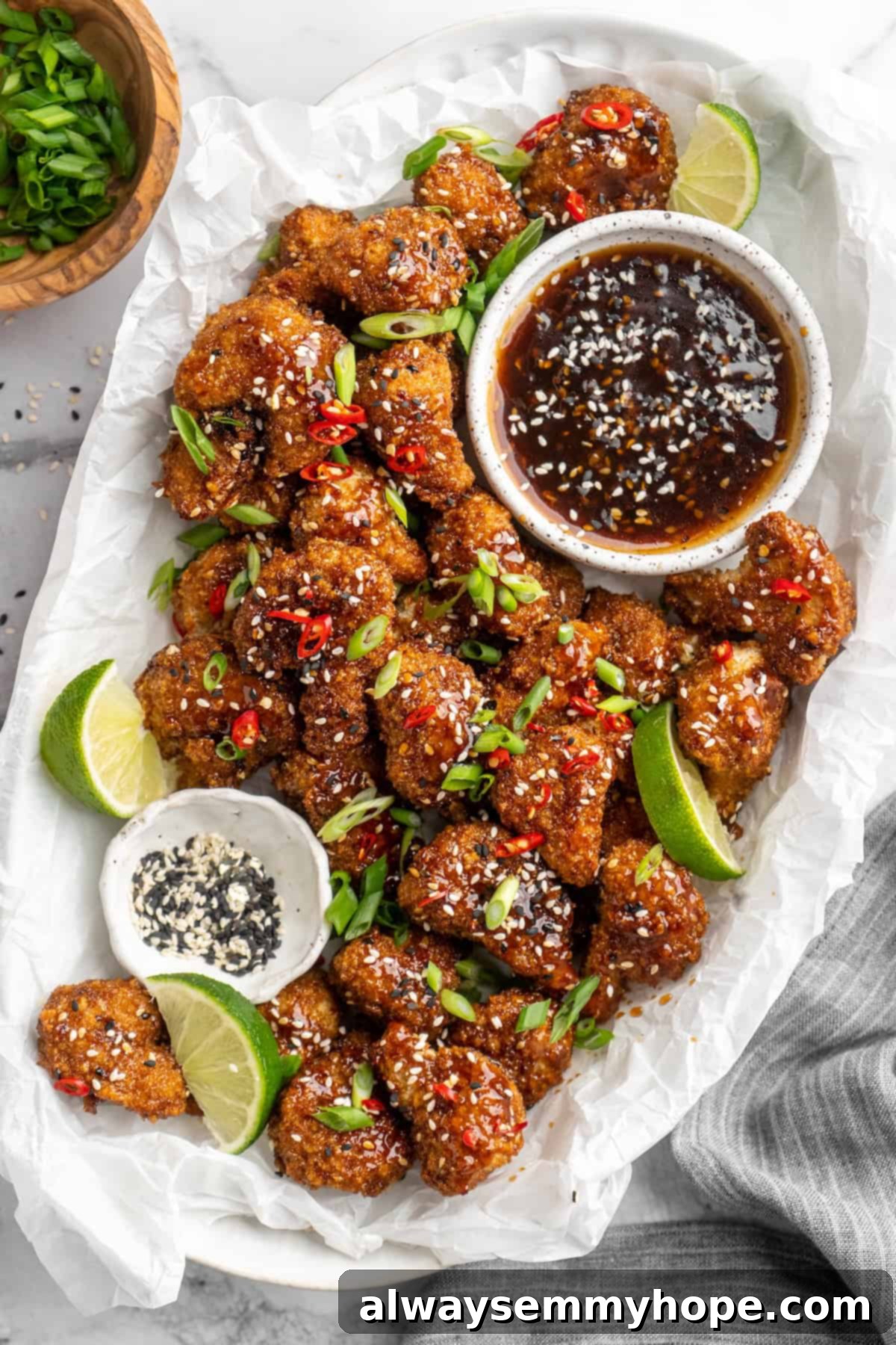 Platter of General Tso cauliflower with lime wedges and bowl of sauce