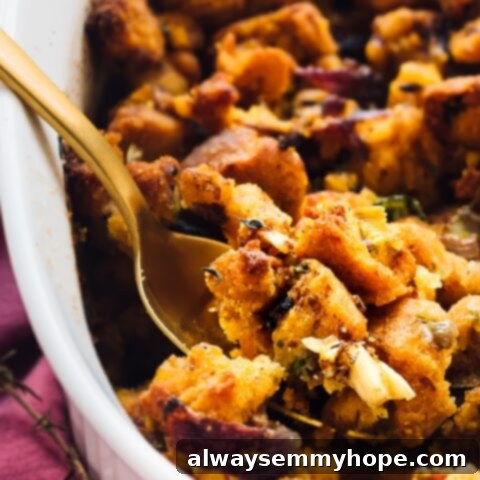 80+ Vegan Thanksgiving Feast Recipes 44 A golden-brown vegan cornbread stuffing, baked in a casserole dish, with visible herbs and vegetables.