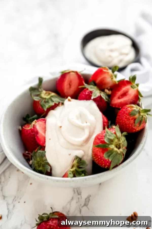 Vegan Cashew Whipped Cream 4 A bowl of fresh, vibrant strawberries, generously topped with fluffy vegan cashew whipped cream.