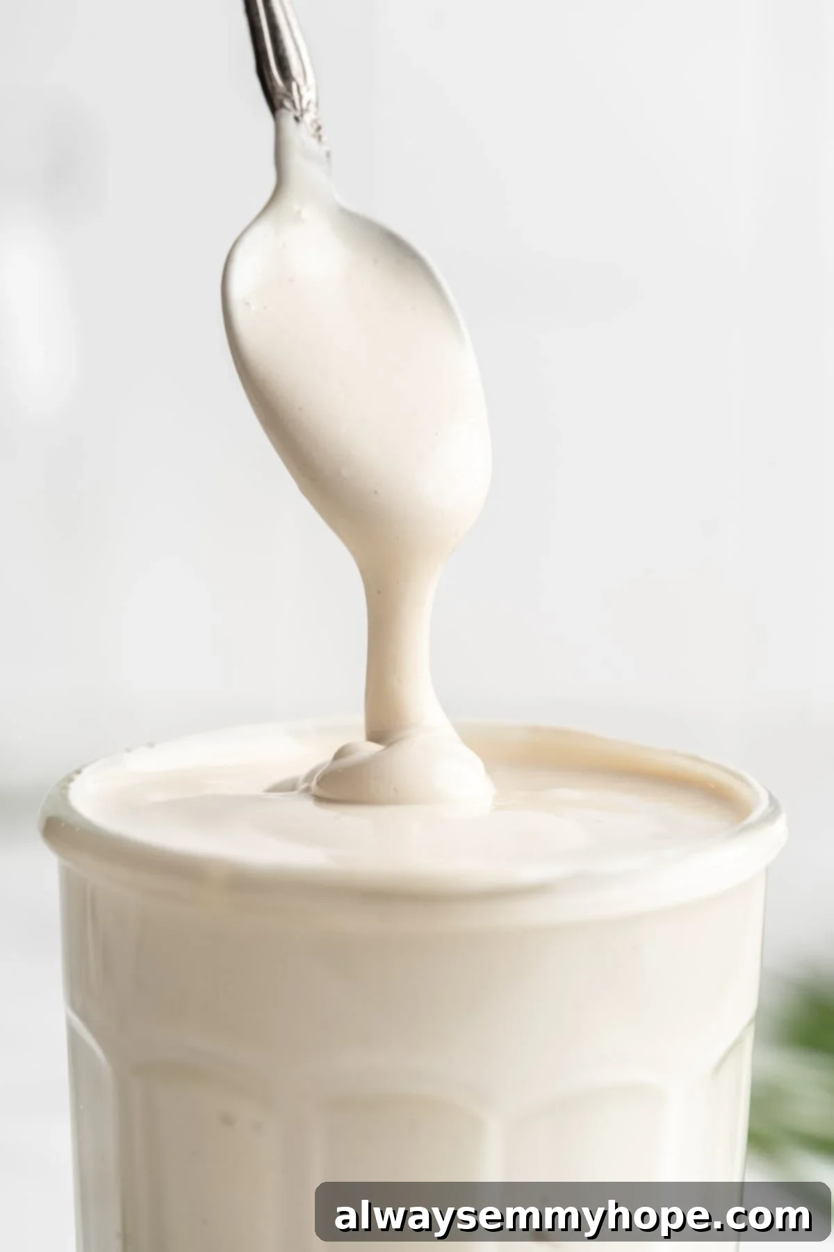 This vegan sour cream recipe is thick, creamy and tangy—and you only need 5 ingredients! Use it all the ways you use traditional sour cream. Spoon dripping vegan sour cream into jar