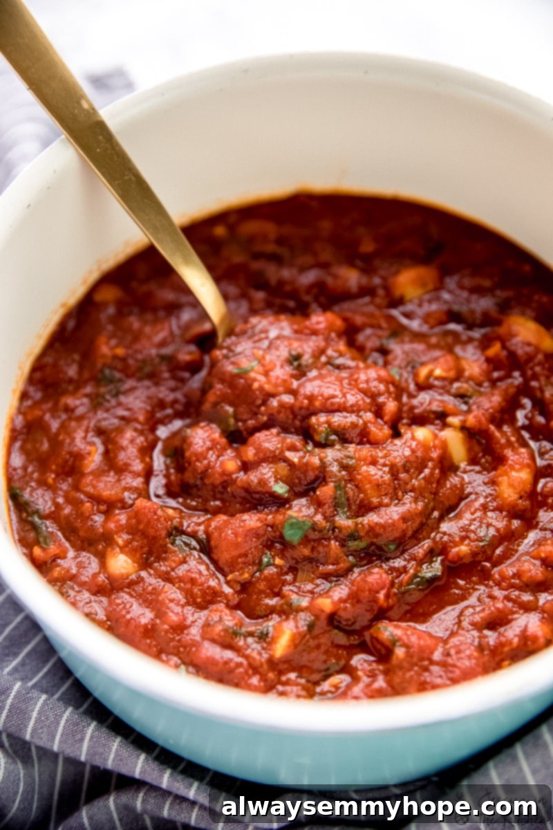 Garlicky tomato sauce simmering in a blue pot with a gold spoon.