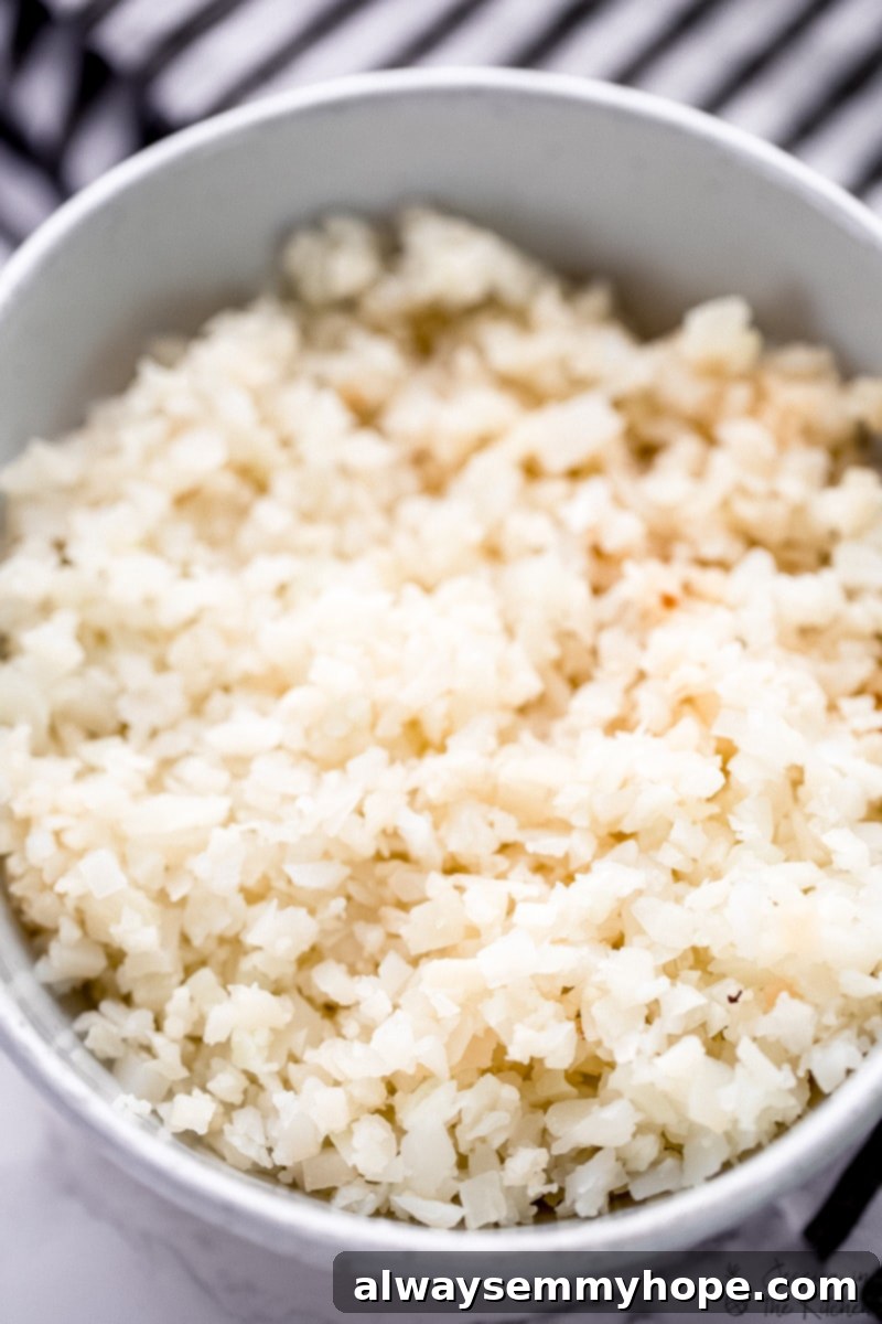 A close-up shot of fluffy, perfectly riced cauliflower in a bowl, ready for cooking.