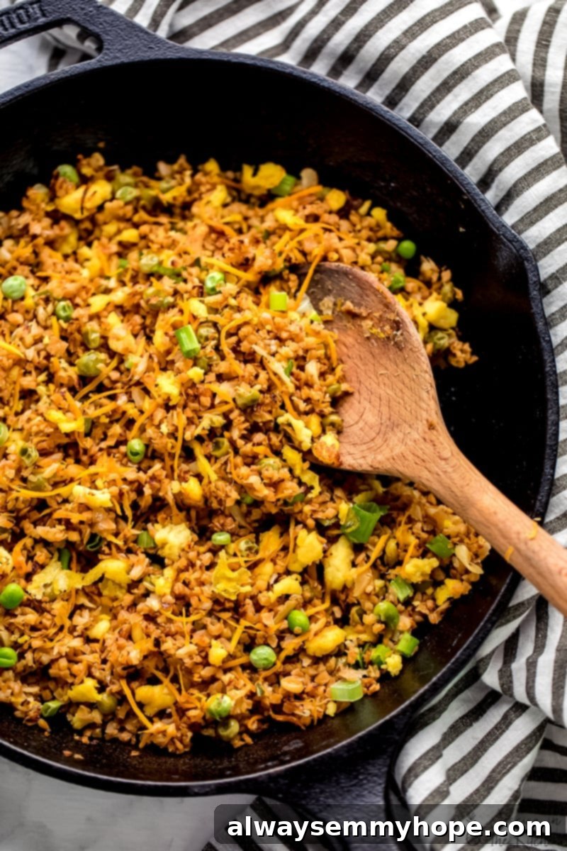 Top-down shot of a wooden spoon stirring a generous portion of freshly cooked vegan cauliflower fried rice.