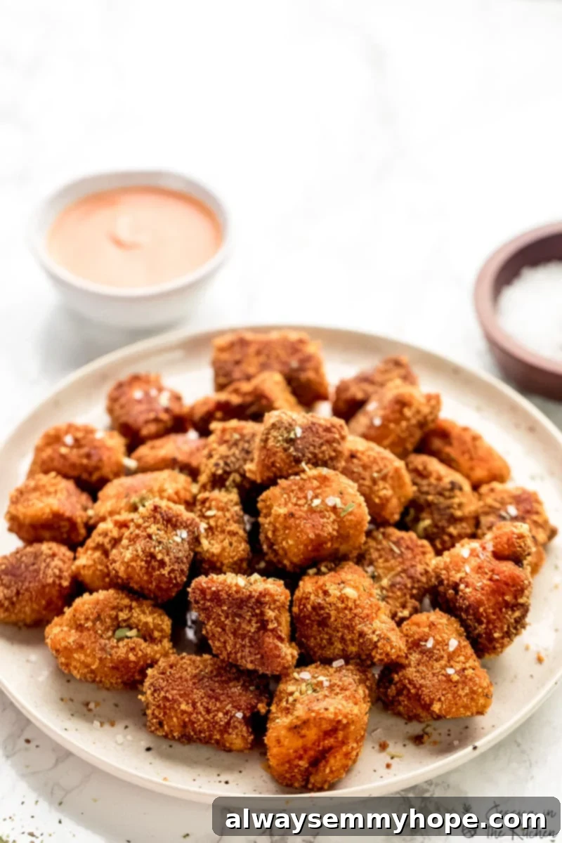 Crispy Crunchy Vegan Chicken Nuggets 5 Vegan chicken nuggets on a plate with a dip in the background a plate of sprinkling salt.