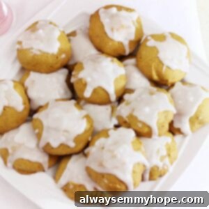 A batch of pumpkin cookies on a white plate, showcasing their soft texture and generous icing.
