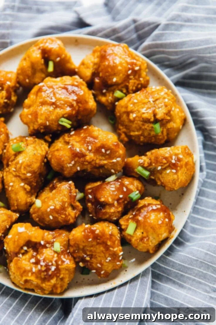 Score Big with 30 Vegan Super Bowl Recipes 18 Sweet and Sticky Orange Cauliflower Bites in a bowl, garnished with orange zest.