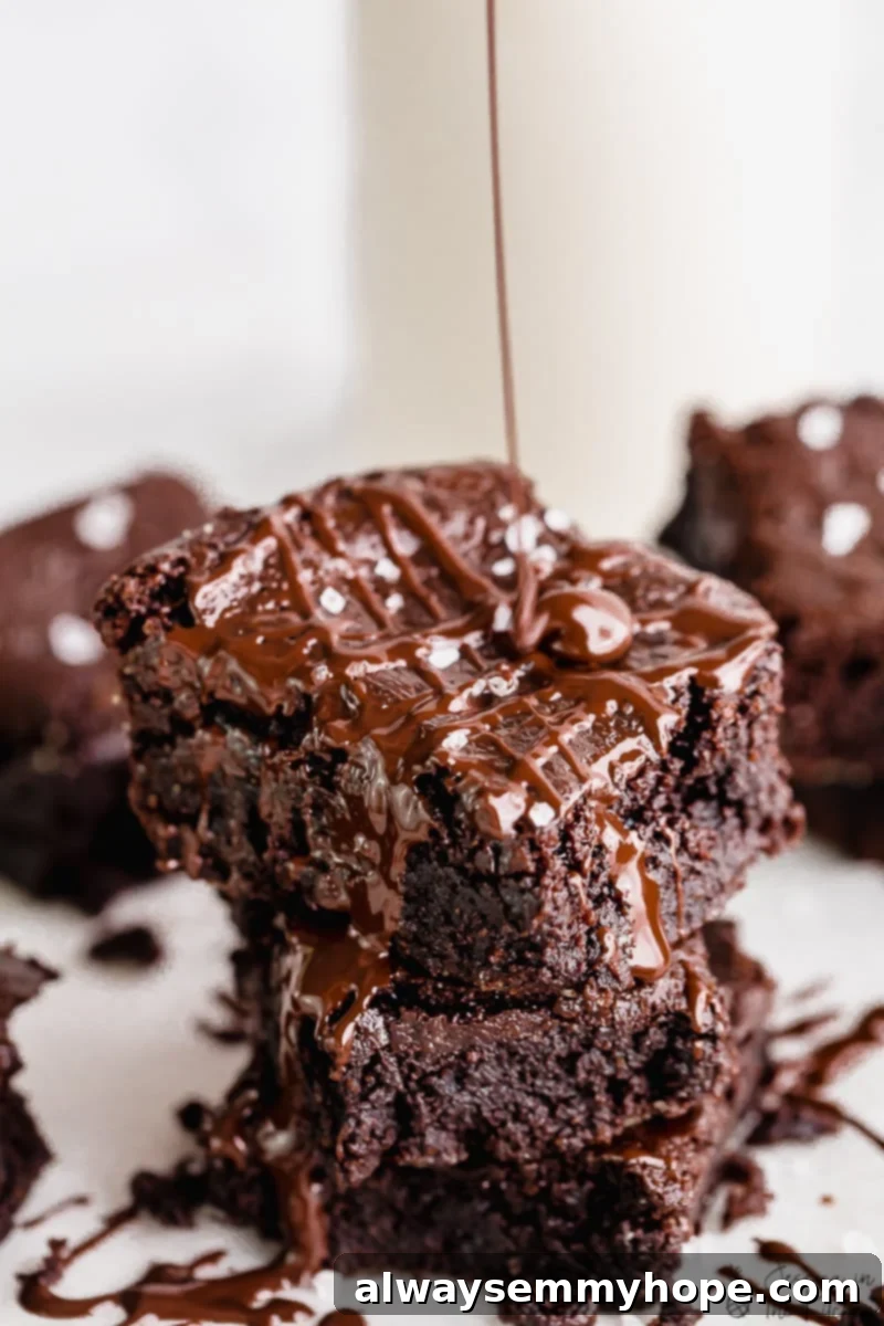 One Bowl Fudgy Vegan Gluten Free Almond Flour Brownies 2 Rich, fudgy Vegan Almond Flour Brownies stacked on each other with chocolate drizzle.