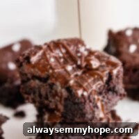 One Bowl Fudgy Vegan Gluten Free Almond Flour Brownies 7 Vegan brownies stacked on each other as chocolate drizzles over it.