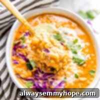 Creamy Vegan Coconut Curry Lentil Soup 2 A close-up of a bowl of creamy vegan coconut curry lentil soup, with a spoon lifting a portion, revealing the texture of the lentils and the rich curry broth.