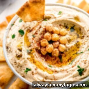 The Ultimate Homemade Hummus 6 A bowl of homemade hummus, topped with chickpeas and surrounded by pita chips.