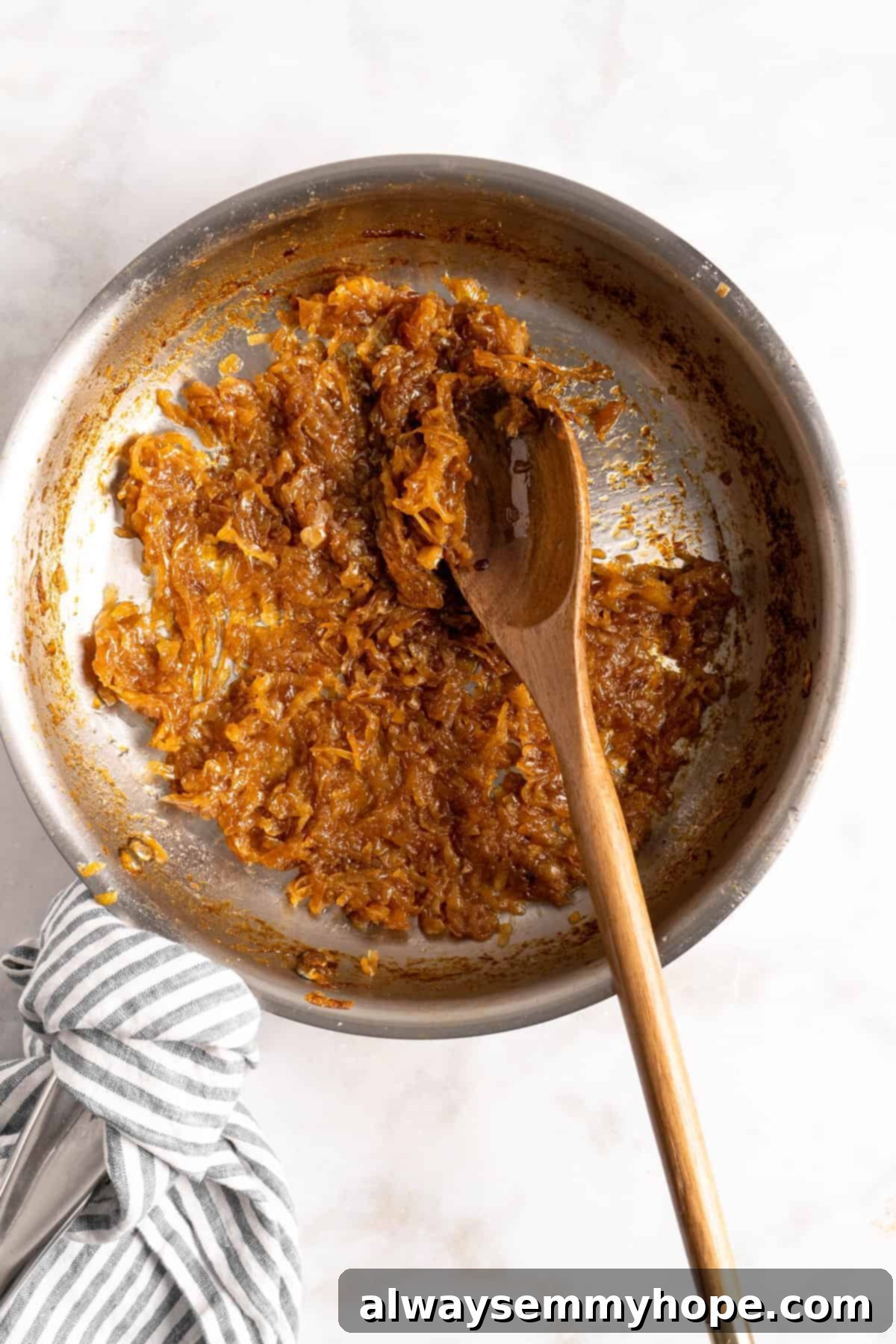 Learn how to caramelize onions the right way for sweet, deeply browned, jammy onions to add to your favorite meals and recipes! Stirring deeply browned caramelized onions in a cast iron skillet with a wooden spoon