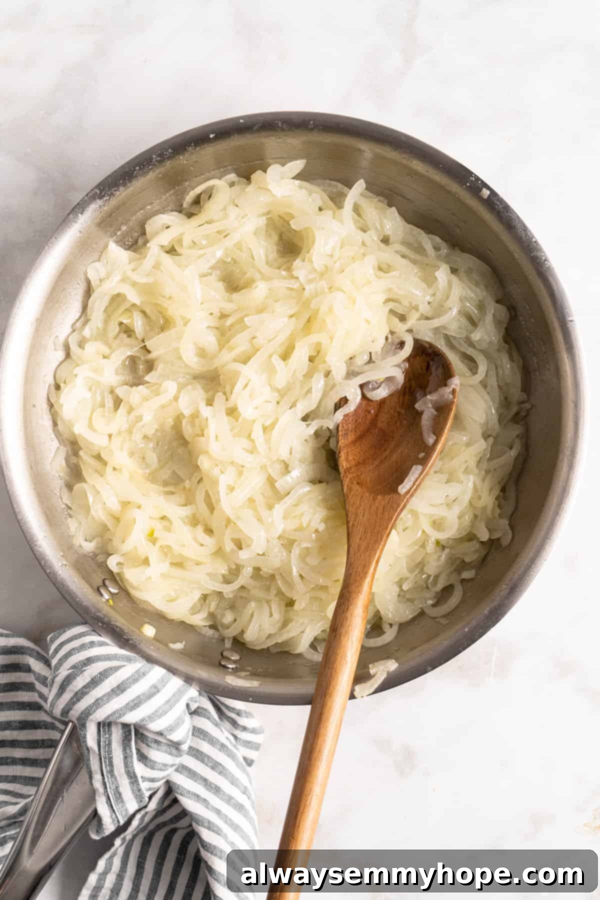 Learn how to caramelize onions the right way for sweet, deeply browned, jammy onions to add to your favorite meals and recipes! Translucent, softened onions being stirred in a skillet with a wooden spoon