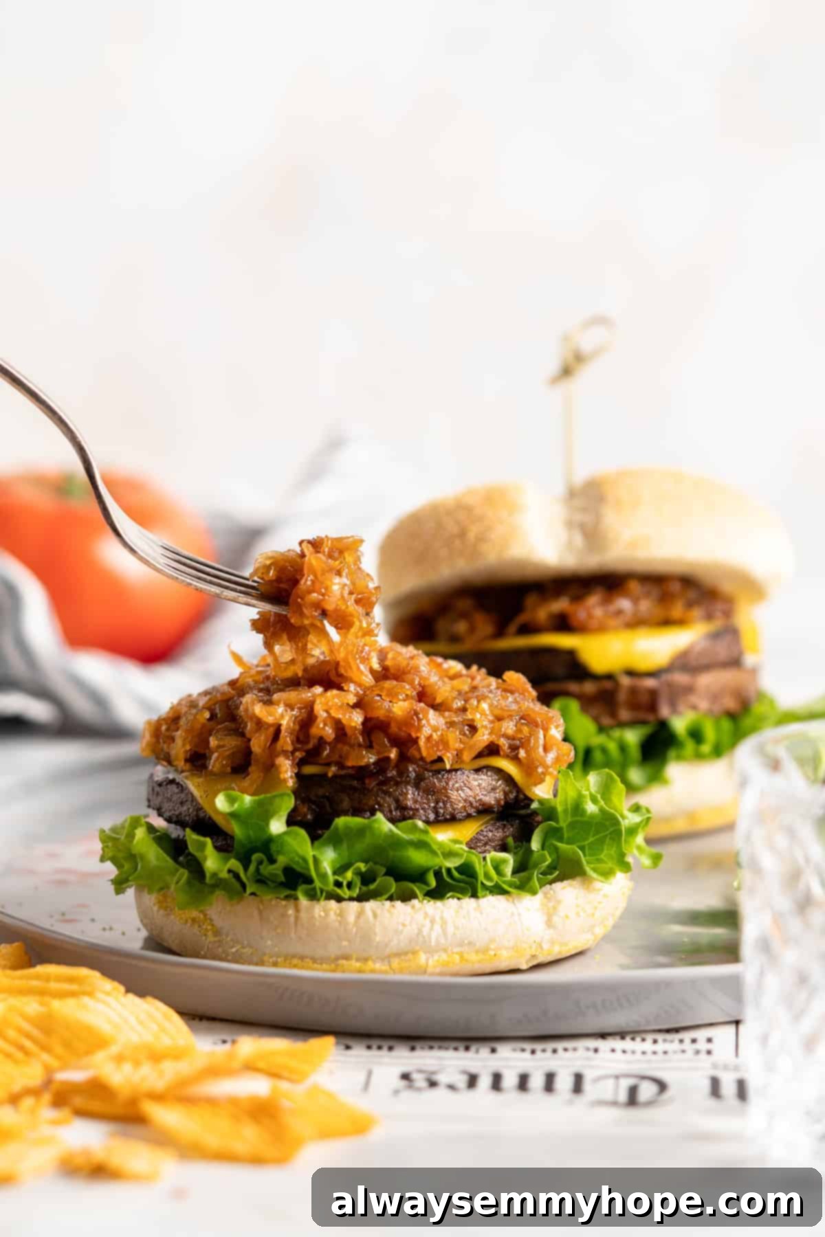 Learn how to caramelize onions the right way for sweet, deeply browned, jammy onions to add to your favorite meals and recipes! Placing caramelized onions onto a veggie burger patty with a fork