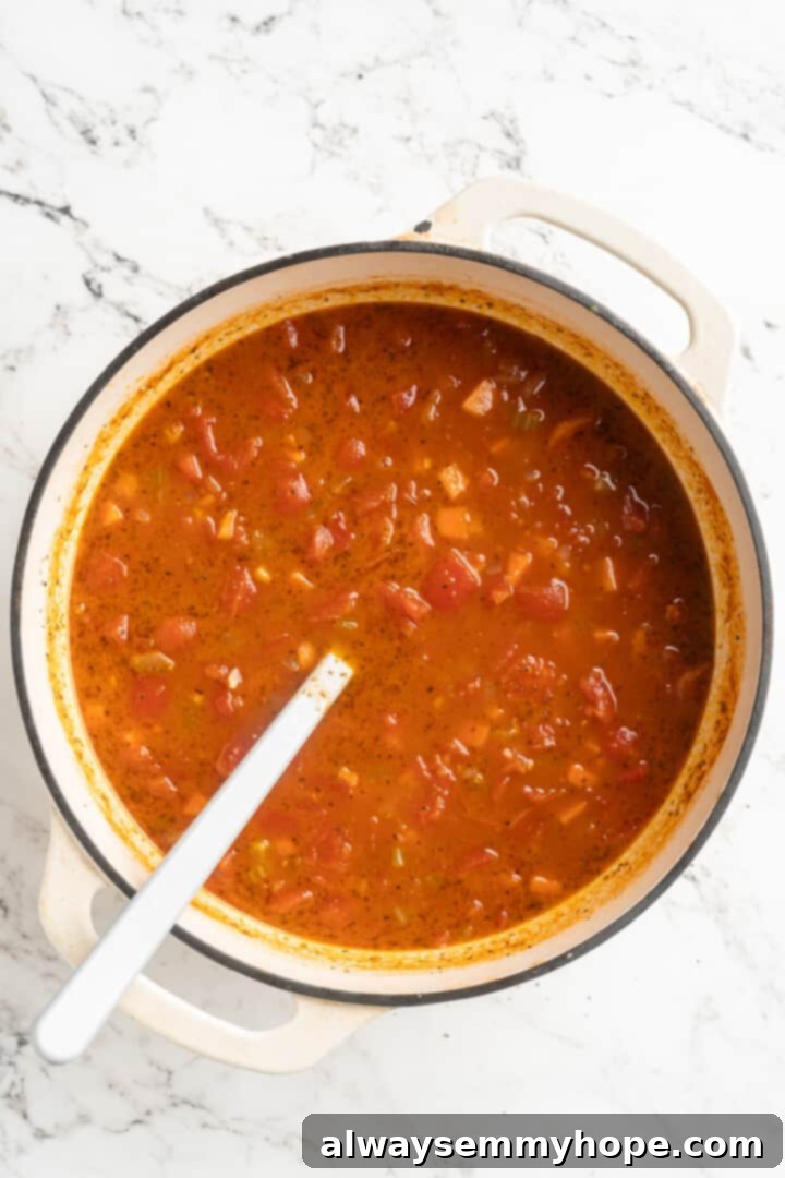 Overhead view of the simmered tomato soup in the pot, prior to blending, showing the softened vegetables and rich color.