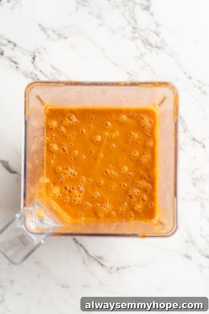 Overhead view of the tomato soup being pureed in a high-speed blender, showing its transformation into a smooth consistency.