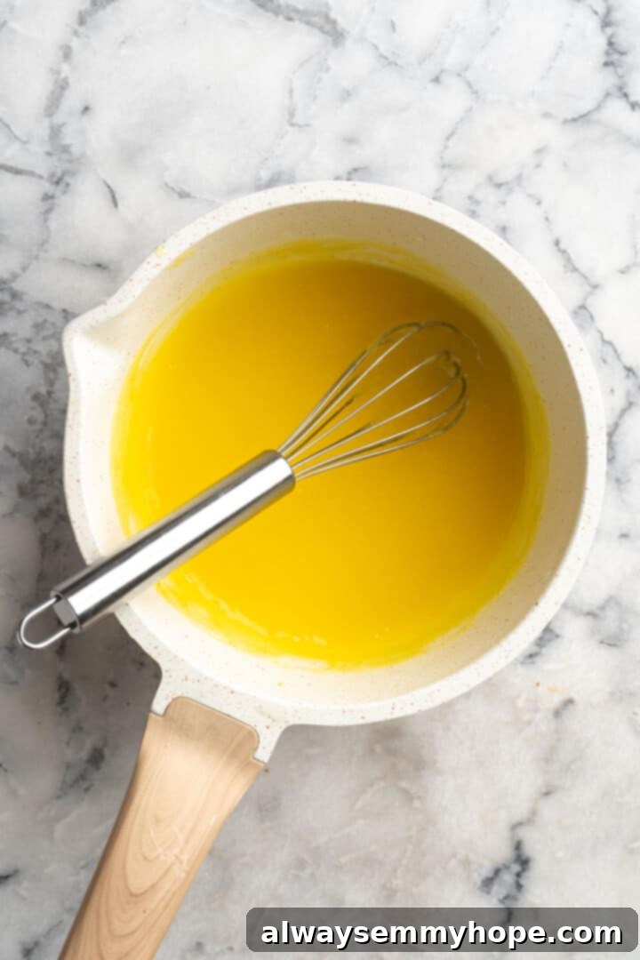 Overhead view of vegan lemon curd in saucepan with whisk