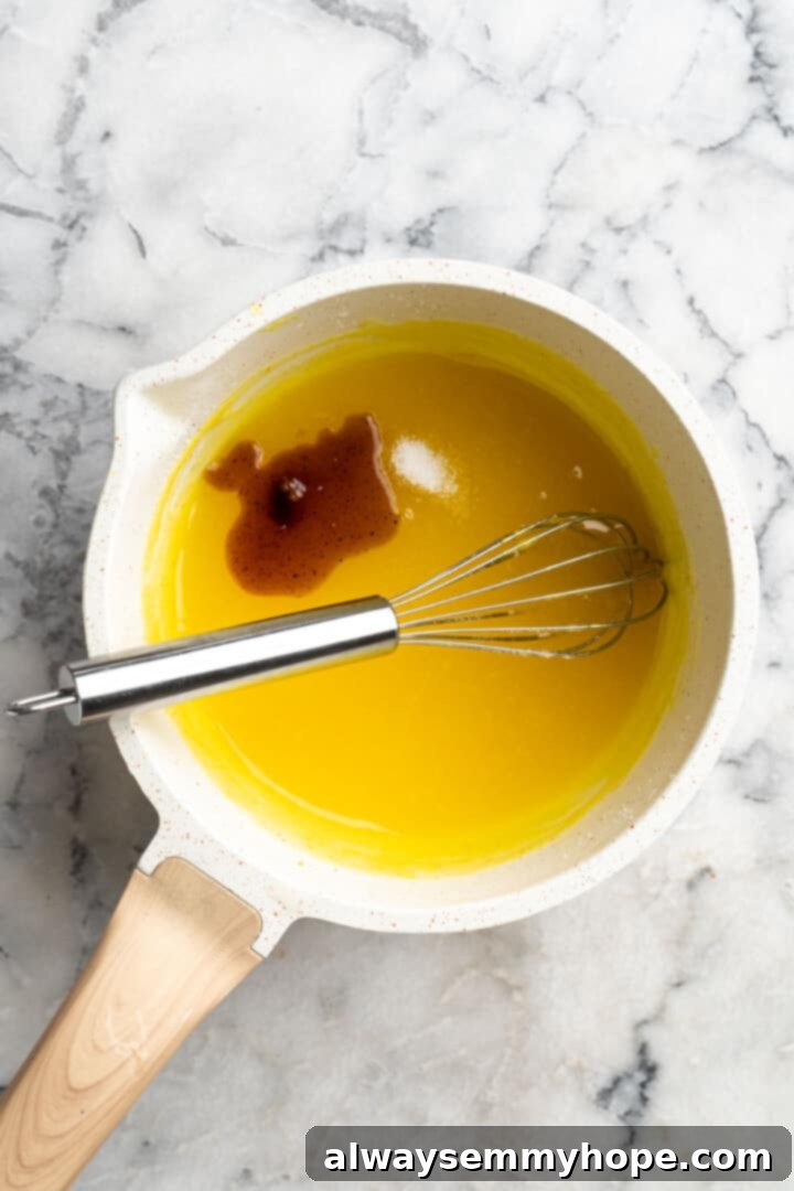 Overhead view of salt and vanilla extract added to saucepan of vegan lemon curd