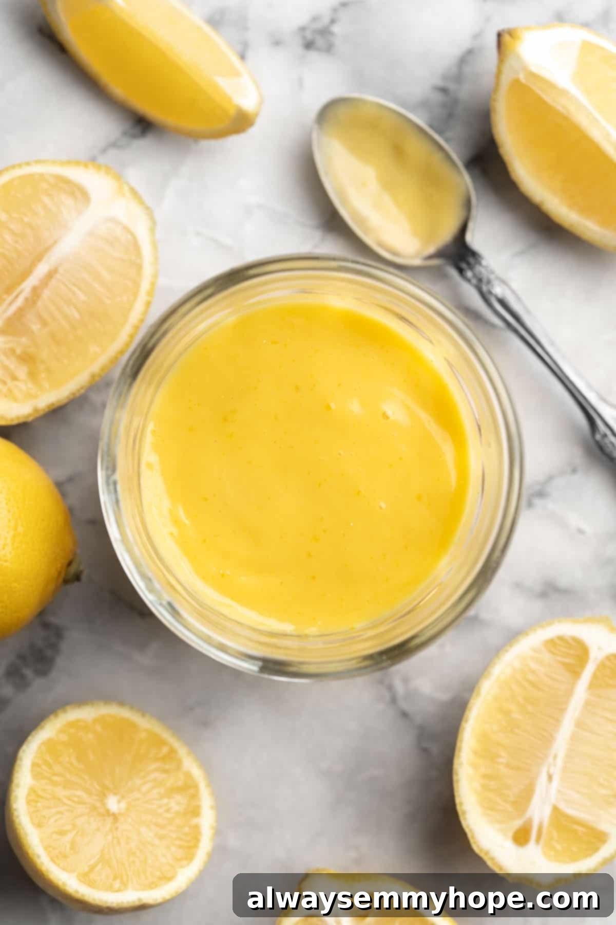 Overhead view of vegan lemon curd in jar, surrounded by halved lemons