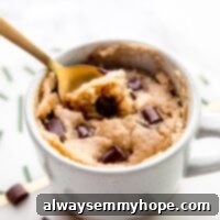 Close up of a spoon resting in a vegan chocolate chip mug cake.