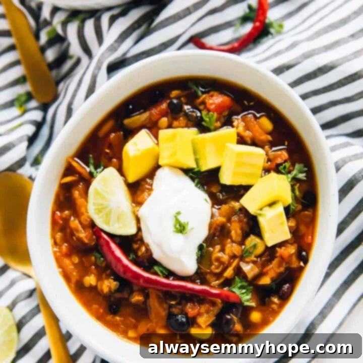 One Pot Red Lentil Chili in a ceramic bowl, topped with fresh avocado and cilantro.