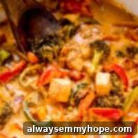 Close up shot of vegan thai red curry in a white pot with a spatula in it.