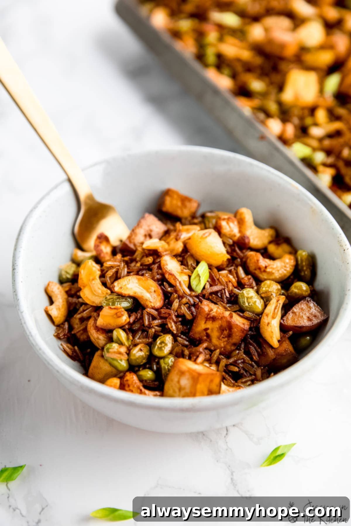 The irresistible crispy texture of our baked vegan fried rice, ready to be devoured! A tempting bowl of extra crispy vegan fried rice, showcasing its baked texture, topped with golden tofu and crunchy cashews.