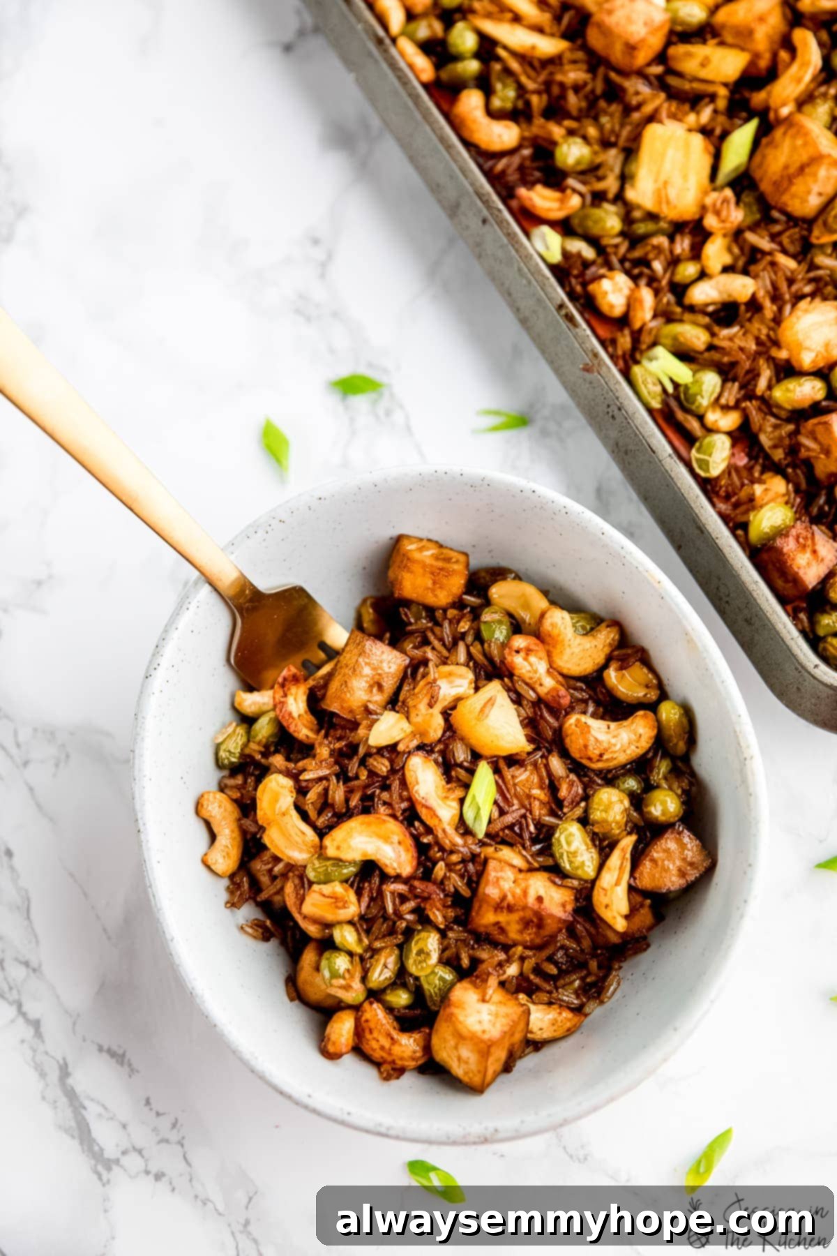 A simple pleasure: a forkful of our perfect sheet pan vegan fried rice. A simple yet inviting bowl of vegan fried rice with a fork, emphasizing its ready-to-eat appeal and comforting texture.
