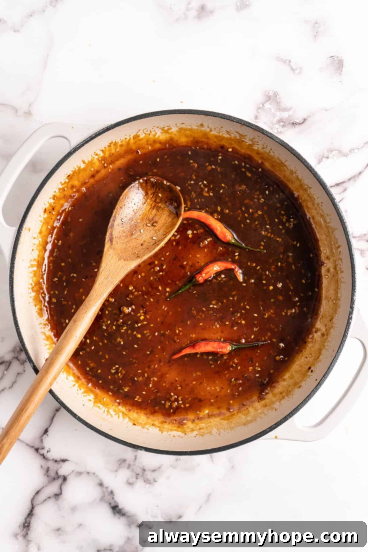 General Tso Sauce simmering in a pan with three whole dried chilies