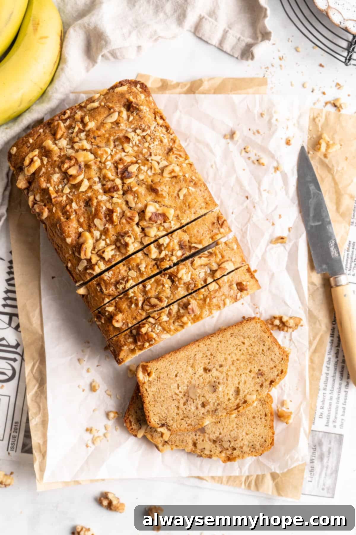 Overhead view of sliced loaf of banana bread set on parchment paper