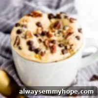 Banana bread mug cake in a mug with a golden spoon in front.