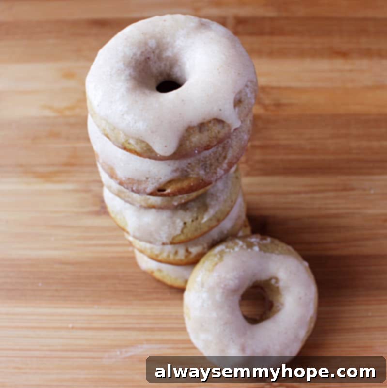 Feast your eyes on these perfect homemade gingerbread doughnuts, complete with a delectable cinnamon-ginger glaze – a holiday baking triumph! A beautiful top-down shot showcasing a generous stack of glazed gingerbread doughnuts on a rustic wooden table, ready to be enjoyed.