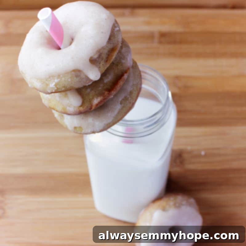 Enjoy the festive delight of homemade gingerbread doughnuts, glazed to perfection and served with a refreshing glass of milk. Three perfectly glazed gingerbread doughnuts displayed on a rustic straw, elegantly arranged with a glass of milk.