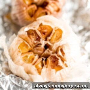 Simple Oven Roasted Garlic 2 Overhead view of two roasted garlic bulbs on foil, glistening.