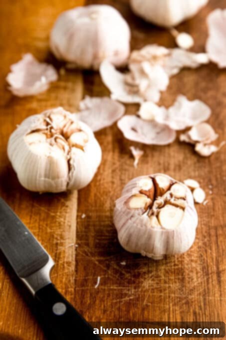 Preparing garlic for roasting: cut tops exposing cloves. Close-up of two garlic heads with their tops precisely cut, revealing the individual cloves inside.