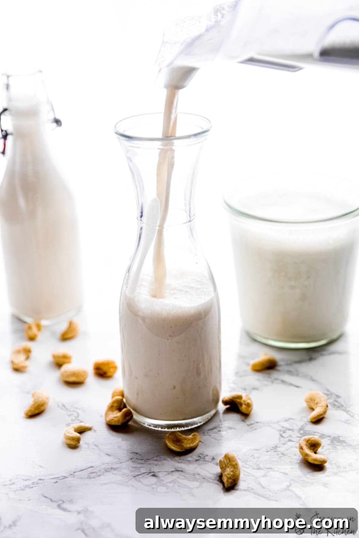 Close-up shot of creamy cashew nut milk being poured into a tall glass bottle, highlighting its luxurious texture.