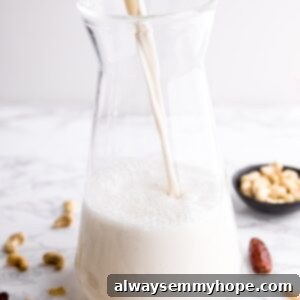 Cashew milk being poured into a glass jug