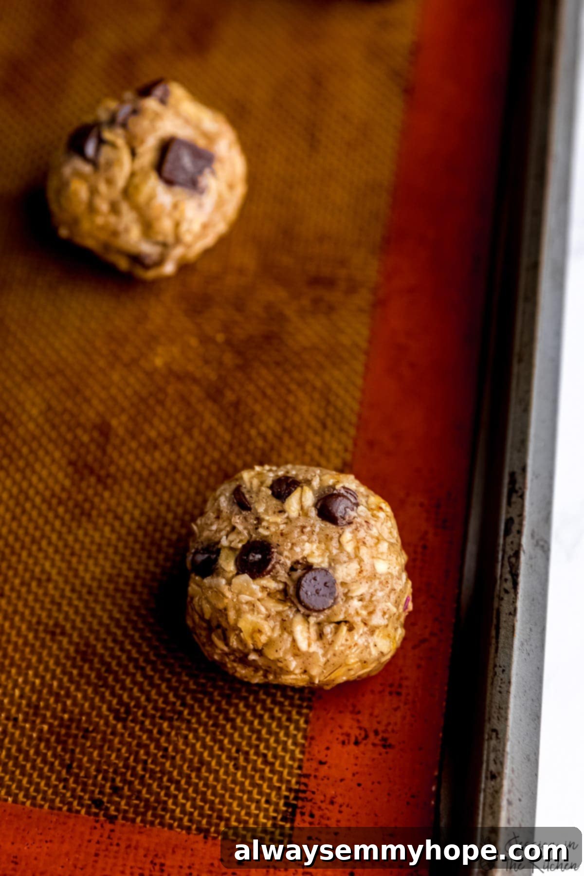 Dough for oatmeal chocolate chip cookies on silpat-lined baking sheet