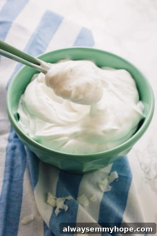 One Can, 20 Vegan Coconut Milk Recipes 3 A spoonful of coconut whipped cream in a green bowl, showcasing its creamy texture.