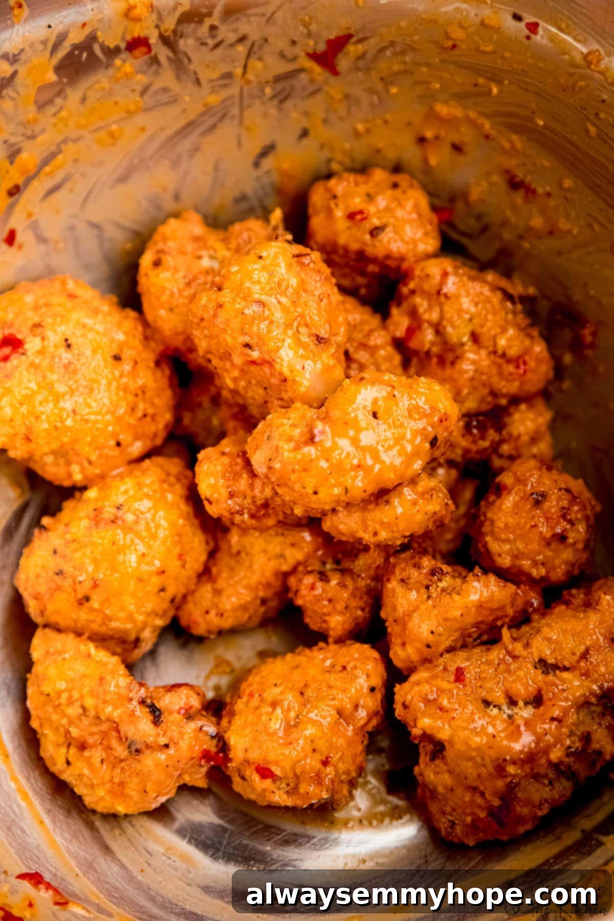 Baked cauliflower wings in a bowl, generously coated with bang bang sauce.