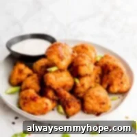 Bang bang cauliflower wings on a plate with dip on the side.
