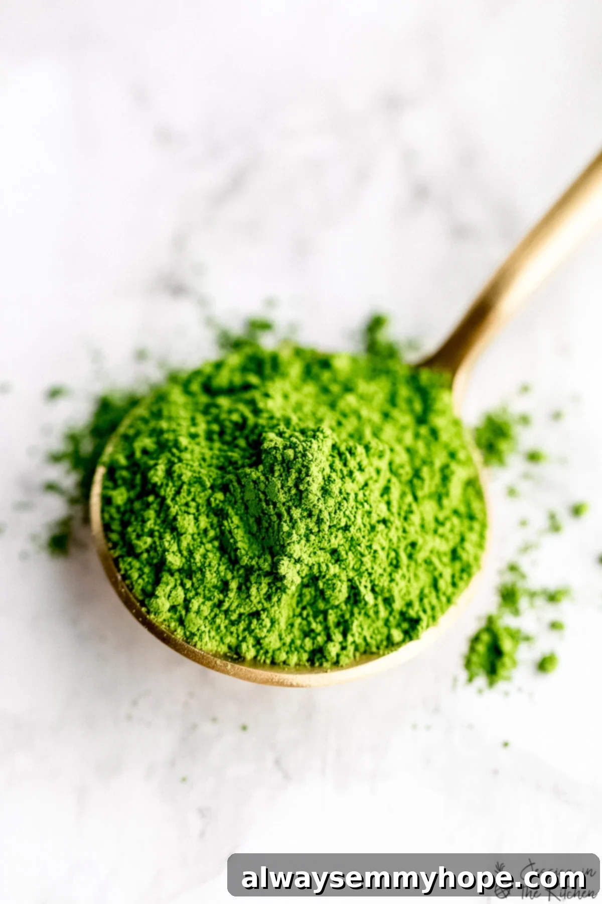 Close-up shot of vibrant green ceremonial grade matcha powder in a delicate gold spoon, ready for use.