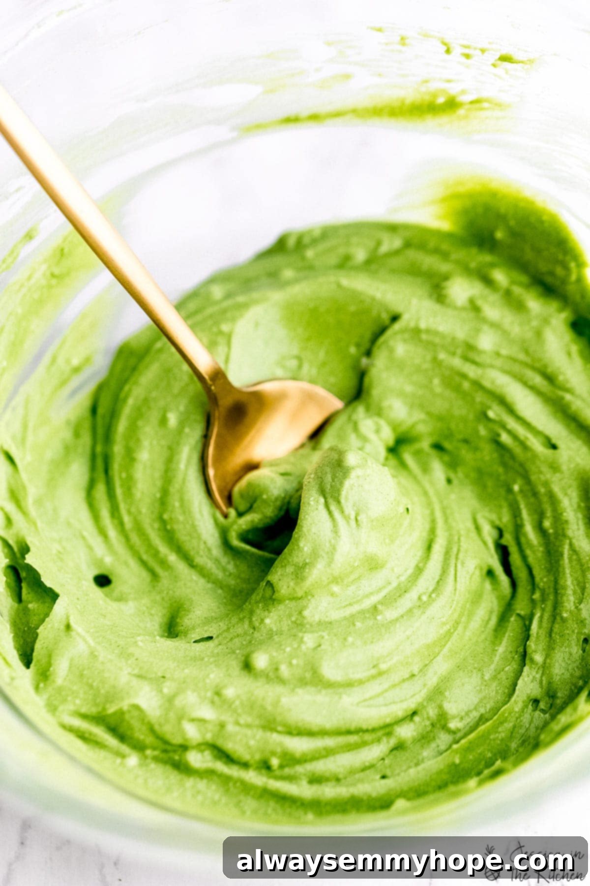 Whipped matcha in a rustic bowl, with a gold spoon resting inside, viewed from a top-down angle, highlighting its smooth, fluffy texture.