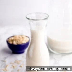 Simple Homemade Oat Milk 2 Side shot of homemade oat milk in a milk jar with a container of oats in the background and a larger jug of oat milk in the background, ready for enjoyment.