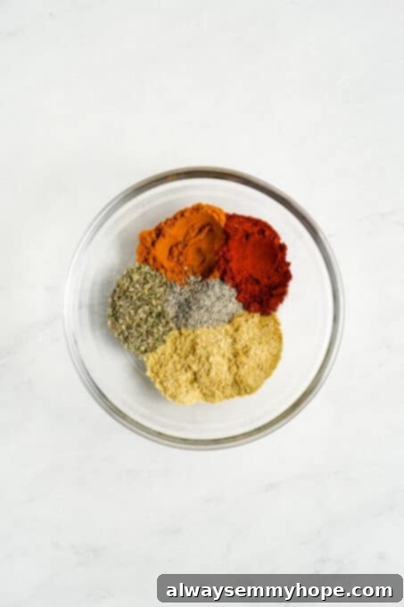 A glass bowl filled with a blend of ground turmeric, paprika, nutritional yeast, and other spices for tofu scramble.
