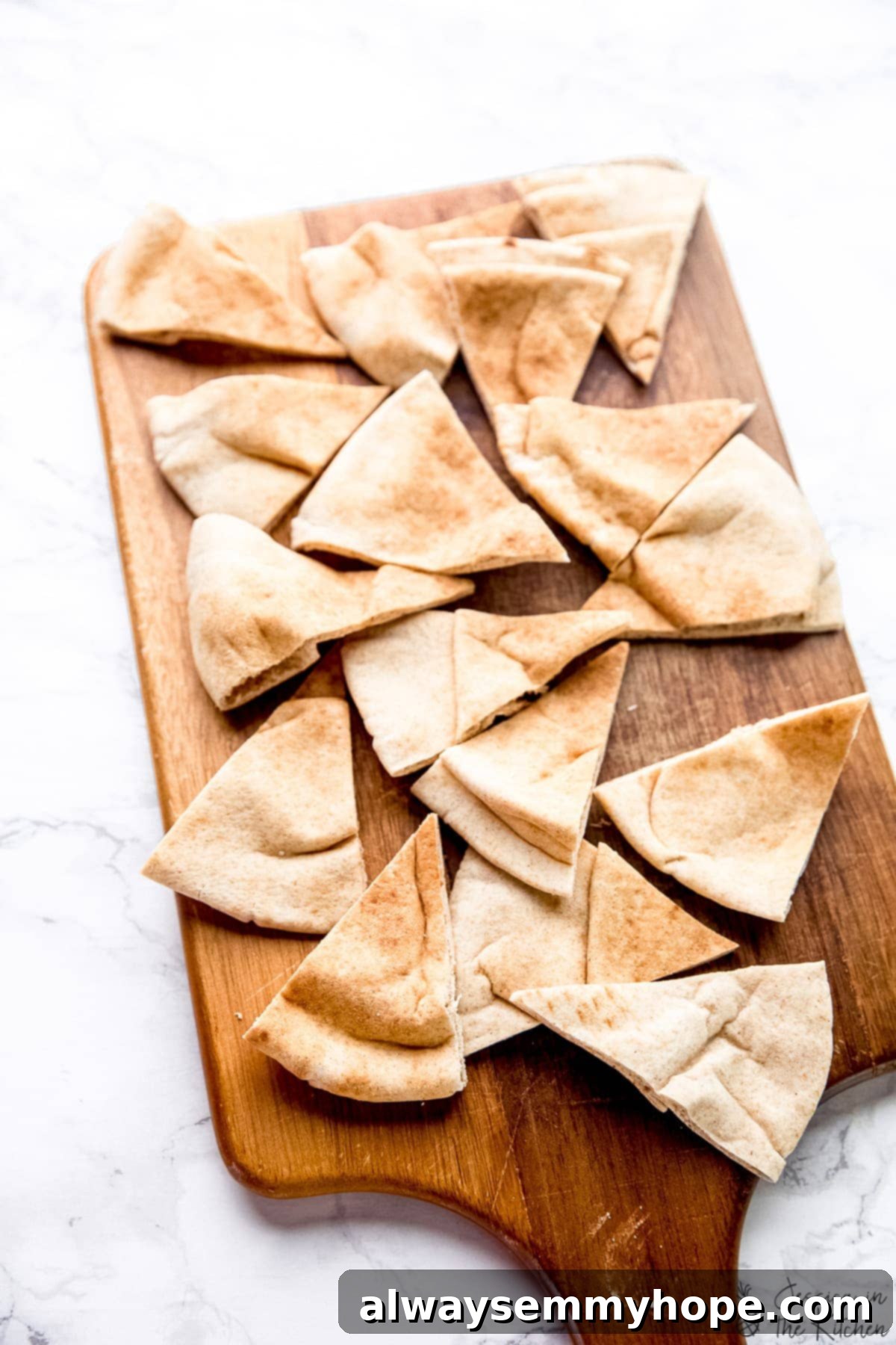 Sliced pita bread triangles on a cutting board, ready to be seasoned and baked into crispy chips.