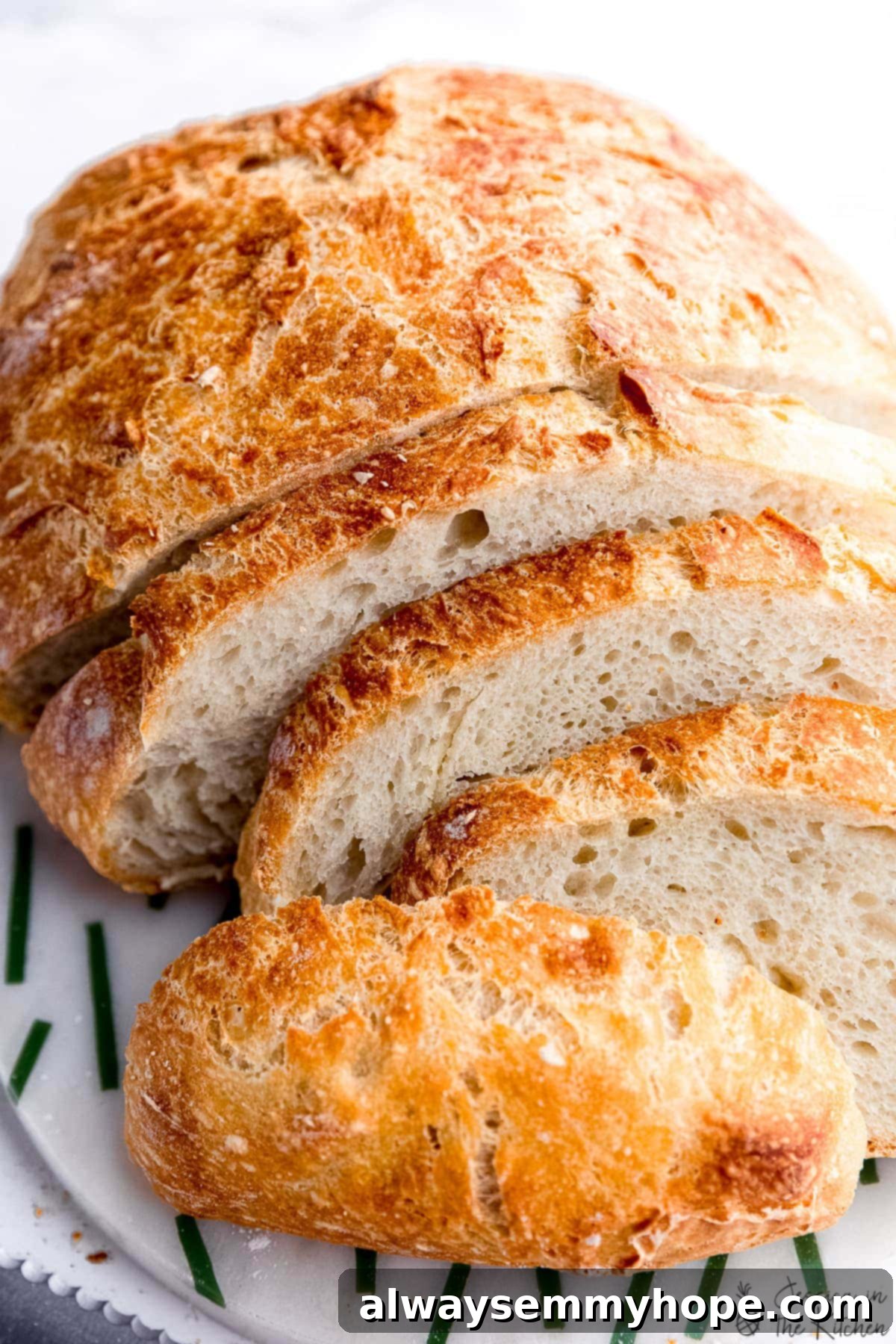 Effortless Dutch Oven Artisan Bread 6 Freshly baked no knead bread, sliced on a wooden cutting board, showcasing its fluffy interior.