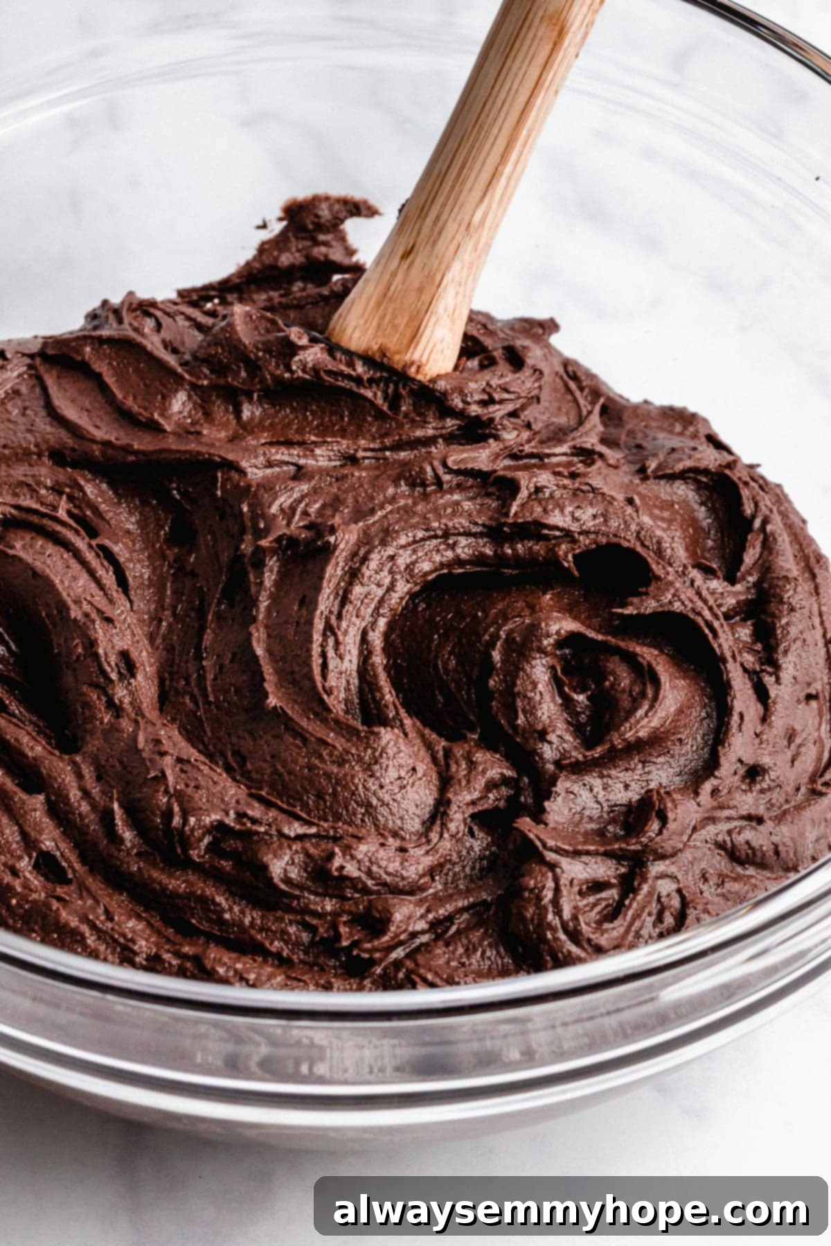 Detailed shot of velvety vegan chocolate frosting in a mixing bowl, showcasing its smooth texture and rich color.
