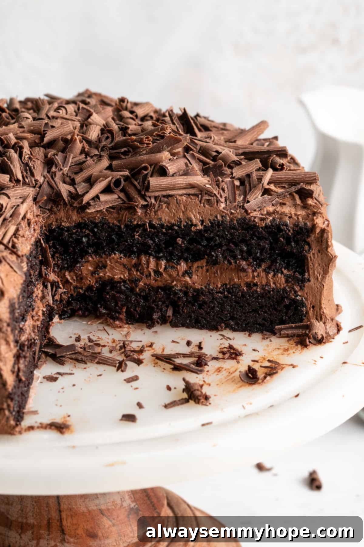 This vegan chocolate cake recipe is the best you'll ever try and the easiest too! Make it yourself and find out why it's a reader favorite. Vegan chocolate cake on cake stand with 2 slices removed.
