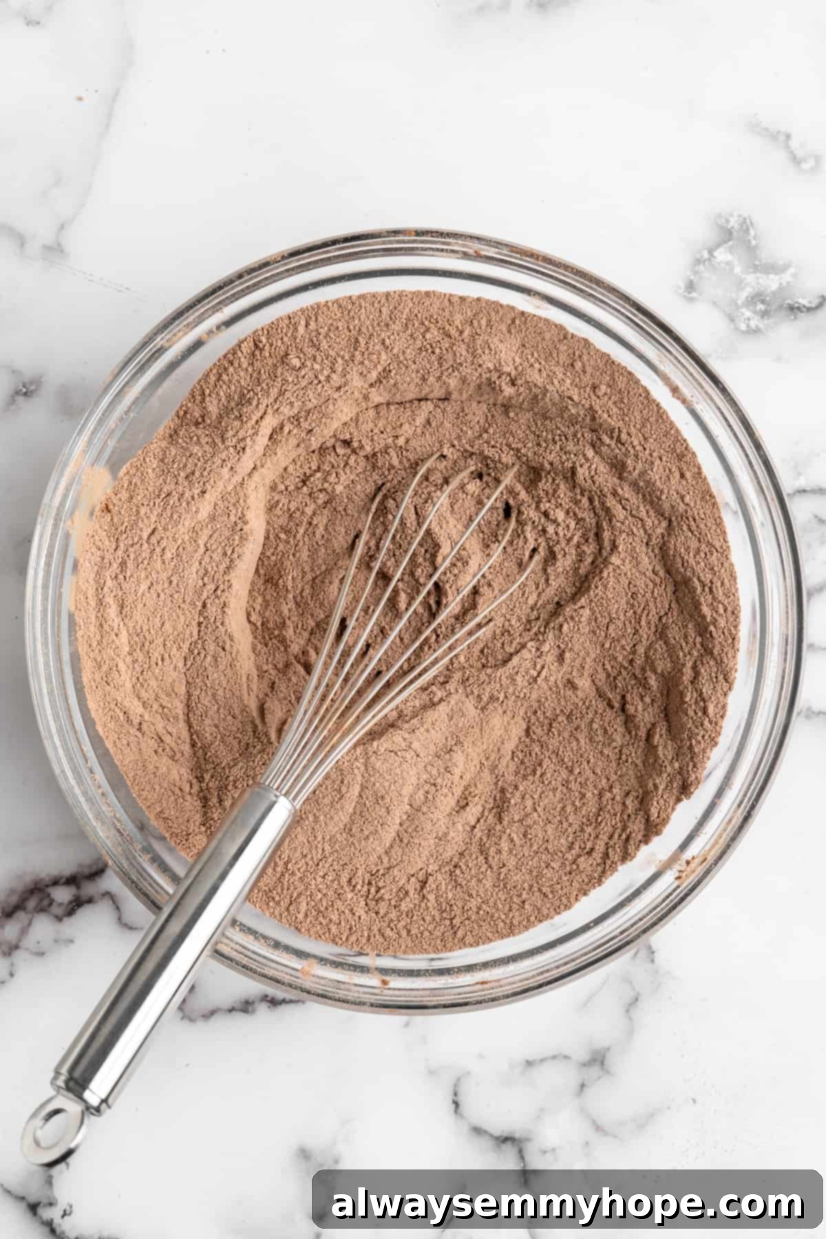 This vegan chocolate cake recipe is the best you'll ever try and the easiest too! Make it yourself and find out why it's a reader favorite. Whisking dry chocolate cake ingredients in glass bowl.